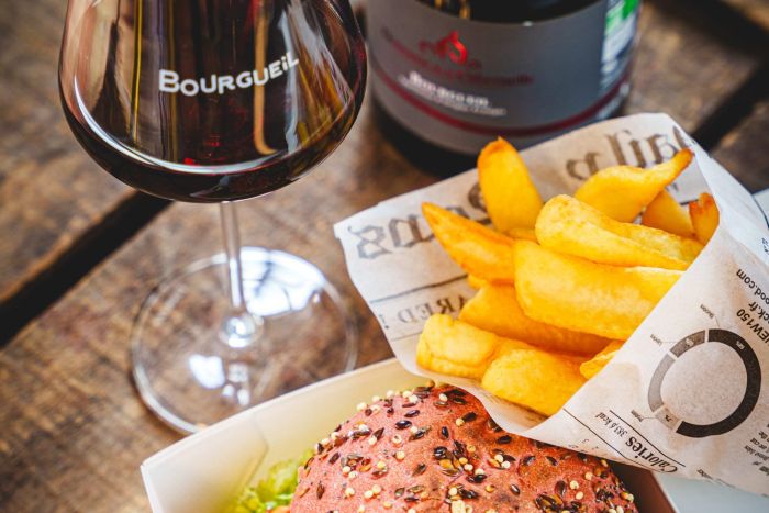 Verre et bouteille de vin rouge de Bourgueil avec un burger et des frites